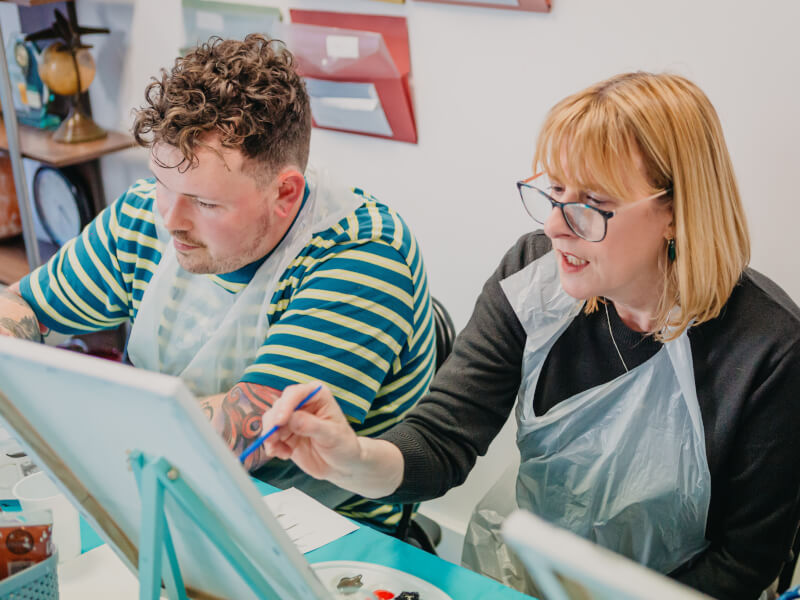A mother and son enjoy a paint and drink event.